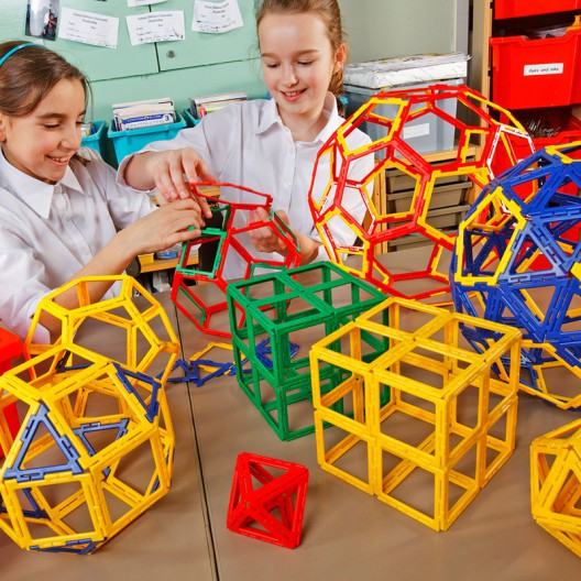 Set Polydron de 223 peces plàstiques calades de colors. Els nens munten cubs i esferes geomètriques gegants a l'aula.