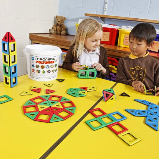 Peces magnètiques Polydron de colors i formes geomètriques per a l'aula, guardades en un cub blanc de plàstic.