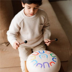 Tambor Tambú+ Soul Serenity blanco de 25cm con 11 notas de colores, tocado por un niño con baquetas de madera.