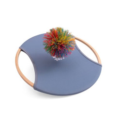 Raqueta circular de bambú amb centre de tela blava elàstica i una pilota de goma amb serrells de colors vibrants.