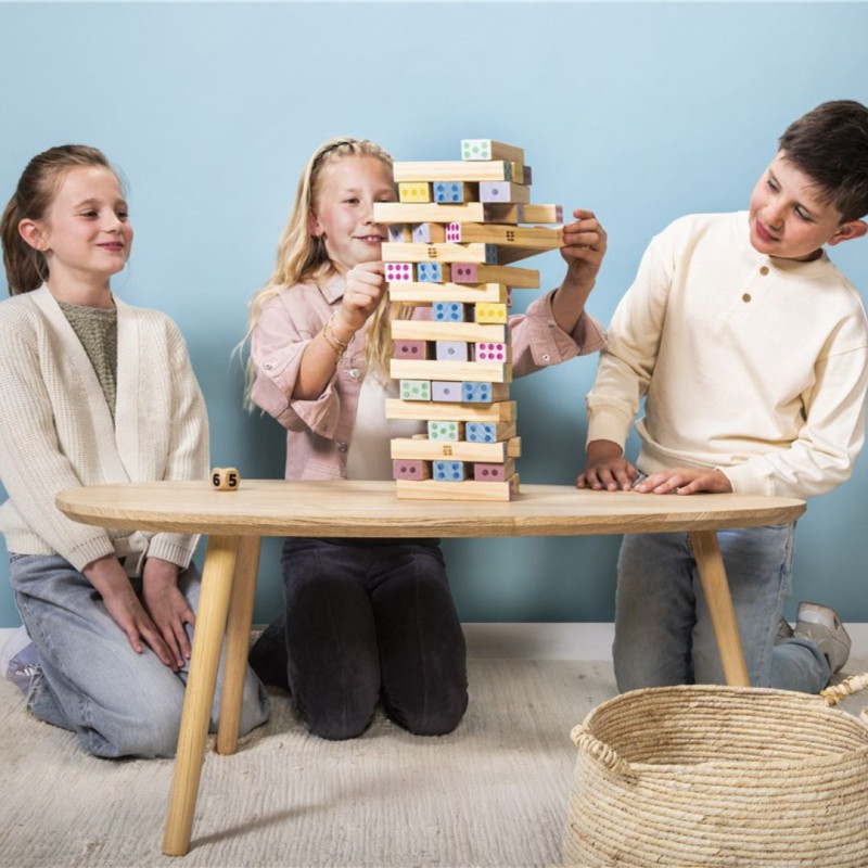 Tres niños juegan con una torre de 48 bloques de madera clara con números impresos sobre una mesa de madera natural.