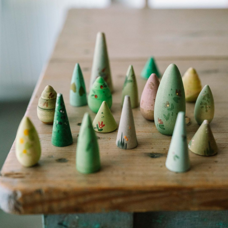 Árboles de madera pintados a mano en tonos verdes y tierra, con formas cónicas y redondeadas para el juego creativo.
