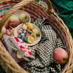 Varietat de petites fruites de fusta Grapat en tons pastel sobre un plat dins d'una cistella de vímet rústica.